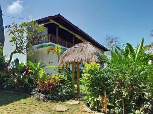 a house with a straw roof in a garden at Lala Homestay Bingin in Uluwatu