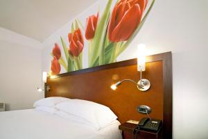 a bedroom with a bed with a painting of red tulips at Hotel du Golf Rosny in Rosny-sous-Bois