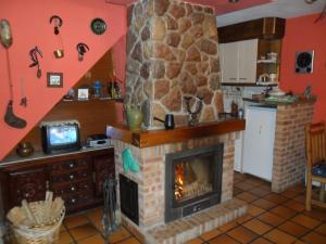 Casa Rural La Rectoral De Tuiza في Tuiza de Arriba: غرفة معيشة مع موقد من الطوب في مطبخ