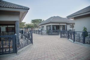 a fence in front of two houses and a driveway at MC Apartments in Lusaka