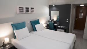 a hotel room with two beds and a desk at Capsis Hotel Thessaloniki in Thessaloniki