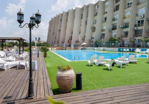 a hotel with a pool and chairs and a building at Ha-aliya Sea View in Nahariyya