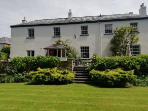 Una gran casa blanca con escaleras en un patio en Buckley Farmhouse, en Sidmouth