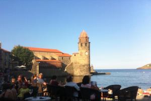 a group of people sitting at tables near the water at Collioure in Collioure