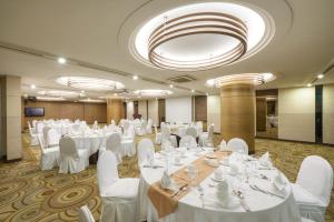 un salón de banquetes con mesas blancas y sillas blancas en Seoul Riviera Hotel, en Seúl