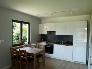 a kitchen with white cabinets and a table with chairs at Grzybowo Dom wakacyjny in Grzybowo