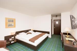 コッヘル・アム・ゼーにあるHotel Alpenhof Postillionの大きなベッドとデスクが備わるホテルルームです。