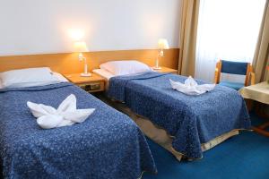 two beds in a hotel room with white flowers on them at Centrum Kołobrzeg in Kołobrzeg