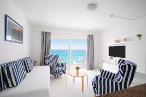 a living room with blue and white chairs and a television at Apartamentos Cabrera in Puerto del Carmen