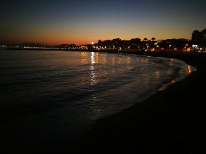 a beach at night with the lights reflecting in the water at Huelintown in Málaga