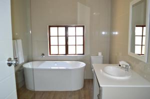 a white bathroom with a tub and a sink at The Wilderness Hotel in Wilderness