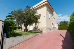 a house with a tree and a red brick driveway at Villa Alzina alojamiento vacacional a 10 minutos de la playa de Cala Millor, Mallorca in Cala Millor