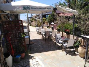 a patio with tables and chairs and an umbrella at Potamaki Studios & Apartments in Stoupa