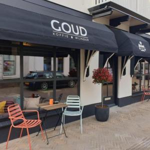 Kamers van Goud في Katwijk aan Zee: مطعم بطاولة وكراسي تحت مظلة سوداء