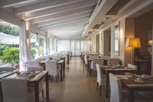 a restaurant with wooden tables and white chairs at Villa Martini in Castiglioncello