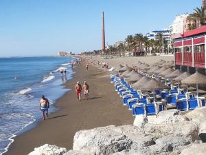 a group of people walking on a beach with umbrellas at Huelintown in Málaga