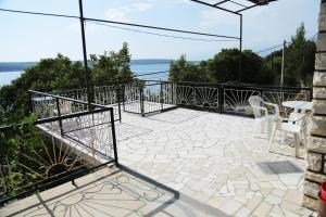 a patio with white chairs and a view of the water at Apartment 51 in Gornji Karin