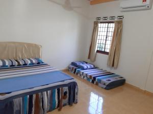 two beds in a room with a window at Pangkor Homestay in Pangkor