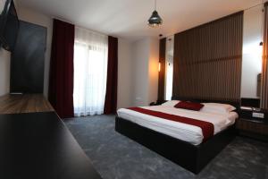 1 dormitorio con 1 cama grande con sábanas rojas y blancas en Prior Hotel en Prizren