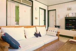 a living room with a white couch with pillows at Hello Project Guesthouse in Jeju