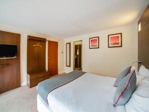 1 dormitorio con 1 cama grande y TV de pantalla plana en The Bridge House Hotel, en Reigate