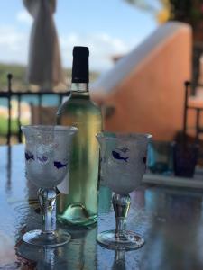 a bottle of wine and two wine glasses on a table at Cala del Faro - Casa di Mare in Porto Cervo