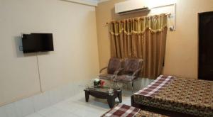 a room with a bed and a chair and a tv at Tourist Lodge Guest House in Kalar Goth