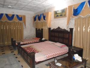 a bedroom with two beds and a table and curtains at Tourist Lodge Guest House in Kalar Goth