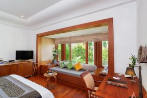 a bedroom with a bed and a tv and a couch at Nakamanda Resort and Spa- SHA Plus in Klong Muang Beach