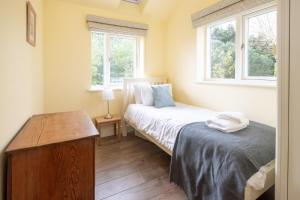 a bedroom with two beds and two windows at Willow House in Aldringham
