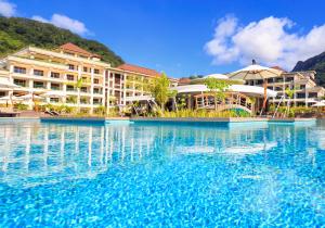 a beach with a pool, chairs, and a swimming pool at Savoy Seychelles Resort & Spa in Beau Vallon