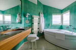 a green tiled bathroom with a tub and a sink at Auberge du Poids Public Logis Hotel in Saint-Félix-Lauragais +54 photos
