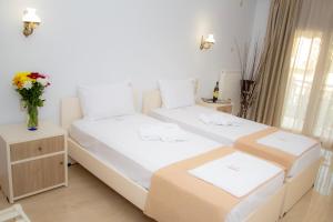 米里纳Hotel Astron的小房间设有两张床,桌子上有鲜花