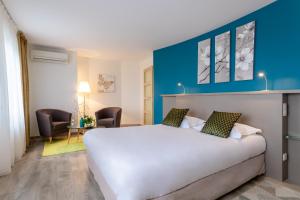 a hotel room with a white bed and a blue wall at Auberge du Poids Public Logis Hotel in Saint-Félix-Lauragais