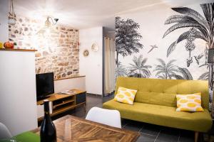ein Wohnzimmer mit einem grünen Sofa und einem TV in der Unterkunft Appartement Denim in Nîmes
