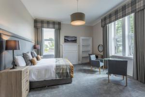 a bedroom with a bed and a desk and chairs at Carlogie House in Carnoustie