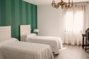 Habitación verde y blanca con 2 camas y lámpara de araña. en Domus Toledo, en Toledo