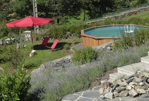 uma piscina com um guarda-sol vermelho e uma cadeira em leKarl em Queyrières