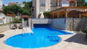 a large blue swimming pool next to a building at Pansion Dragica in Rab