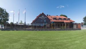 a large building with a green field in front of it at Hotel - Bar Grafaite in Šiauliai