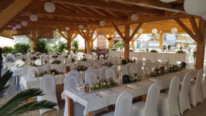 a banquet hall with white tables and white chairs at Pansion Dragica in Rab