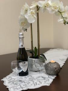 una botella de vino y dos copas en una mesa con flores en Apartament "Marka", en Piła
