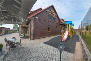a building with a playground next to a table and chairs at Hotel - Bar Grafaite in Šiauliai