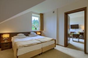 une chambre avec un grand lit et une fenêtre dans l'établissement 4 Pory Roku & Spa, à Krynica-Zdrój
