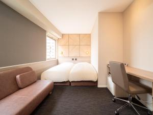 a small room with a bed and a desk and a chair at Super Hotel Tottori Ekimae in Tottori