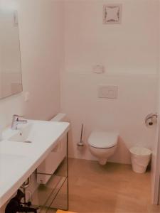 a white bathroom with a toilet and a sink at Appartement UH55 in Neusiedl am See