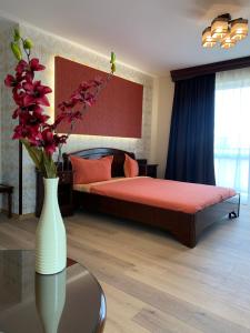 a bedroom with a bed and a vase with flowers on a table at Pensiunea Junior in Cluj-Napoca