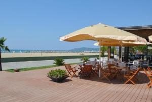 a patio with tables and chairs and an umbrella at Beach Garden Home, Lalzi Bay in Durrës
