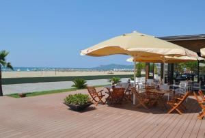 eine Terrasse mit Tischen, Stühlen und einem Sonnenschirm in der Unterkunft Beach Garden Home, Lalzi Bay in Durrës