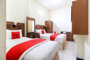 - 2 lits dans une chambre d'hôtel avec des draps rouges et blancs dans l'établissement RedDoorz plus @ Tegal Panggung, à Yogyakarta